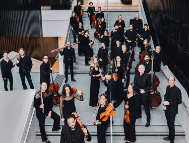 Orchester in schwarzer Kleidung mit Instrumenten auf Treppe