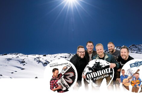 Eine Gruppe von Musikern steht vor einer verschneiten Berglandschaft. Im Hintergrund leuchtet die Sonne am klaren Himmel.