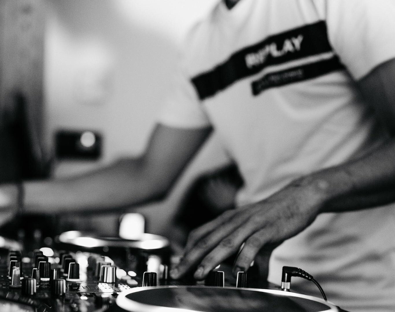 Ein DJ, der an einem Mischpult arbeitet. Die Atmosphäre ist dynamisch und energiegeladen.