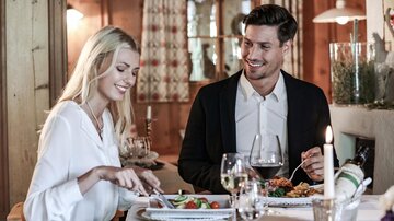 A couple enjoys a romantic dinner in a cozy atmosphere. Delicious dishes and wine glasses are on the table.