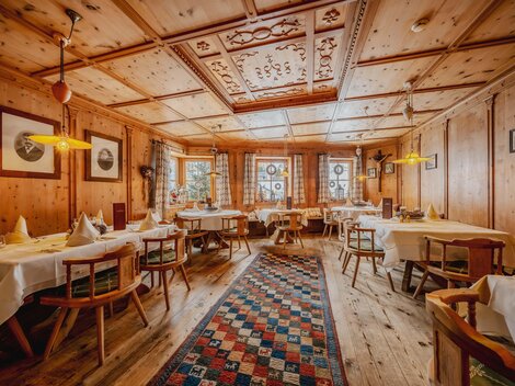 A cozy restaurant with wooden walls and tables. The room is warmly lit and has an inviting ambiance.