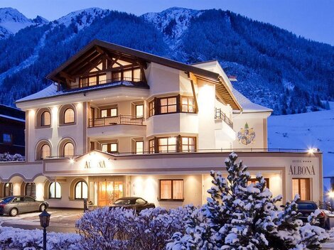 Ein charmantes Hotel in den Bergen, umgeben von Schnee. Die Fassade des Gebäudes strahlt Gemütlichkeit aus und die Atmosphäre ist einladend.