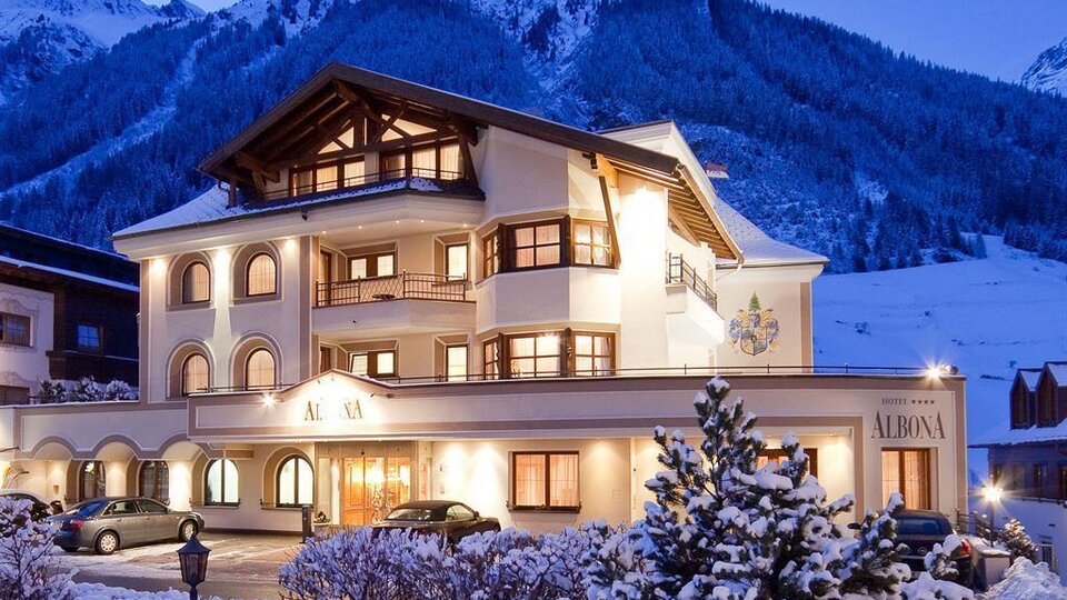 Ein charmantes Hotel in den Bergen, umgeben von Schnee. Die Fassade des Gebäudes strahlt Gemütlichkeit aus und die Atmosphäre ist einladend.
