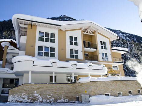 Ein modernes Gebäude in einer schneebedeckten Landschaft. Die Fassade ist hell und einladend, umgeben von Bergen.