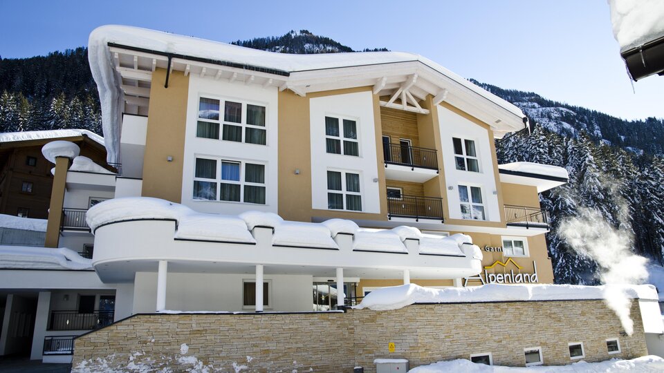 Ein modernes Gebäude in einer schneebedeckten Landschaft. Die Fassade ist hell und einladend, umgeben von Bergen.