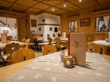Ein gemütliches Restaurant mit Holzvertäfelung und rustikalen Tischen. Die Tische sind sauber gedeckt und es gibt eine einladende Atmosphäre.