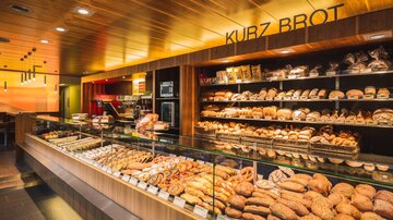 A bakery with a wide selection of fresh bread and pastries. The shelves are full of different types of bread and delicious baked goods.