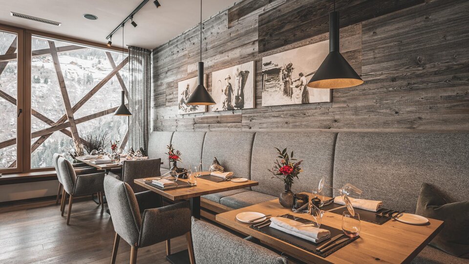 Ein elegantes Restaurant mit Holzwänden und gemütlichen Tischen. Die Atmosphäre ist warm und einladend, mit schönen Dekorationen auf den Tischen.