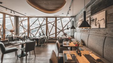 Ein modernes Restaurant mit Holzdekor und großen Fenstern. Der Raum ist stilvoll eingerichtet und bietet einen Blick auf die verschneite Landschaft.