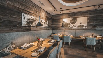 Ein modernes Restaurant mit Holzwänden und eleganten Tischen. Die Atmosphäre ist gemütlich und einladend.