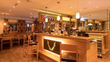 A cozy bar with wooden interior and warm light. The counter is well-equipped and inviting for guests.