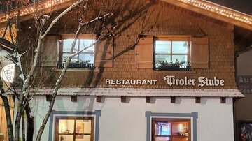 A cozy restaurant in Tyrolean style, surrounded by snow. The facade is festively decorated with lights.