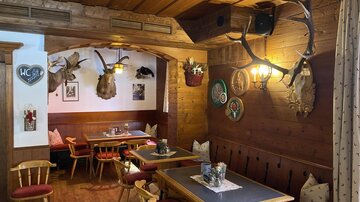 A cozy restaurant with wooden decor and rustic furniture. The walls are adorned with hunting trophies and decorative wall plates.