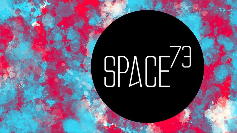 Ein auffälliges, farbenfrohes Hintergrundmuster in Blau und Rot. Das Logo "SPACE73" in der Mitte ist schwarz und modern gestaltet.