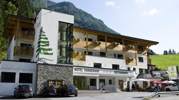 Ein gemütliches Hotel mit einem modernen und traditionellen Design. Es gibt eine Terrasse mit Tischen und Stühlen sowie einen schönen Blick auf die umliegenden Berge.