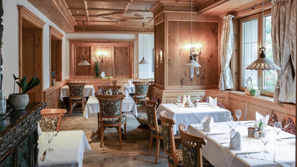 A cozy restaurant with wooden walls and elegantly set tables. Soft lighting creates an inviting atmosphere.