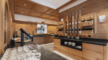 An inviting room with wooden walls and a modern counter area. On the counter are glasses and a variety of foods in decorative containers.