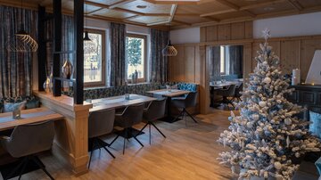 A stylish restaurant with wooden elements and modern furniture. A decorated Christmas tree gives the room a festive atmosphere.