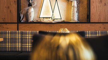Ein stilvolles Interieur mit dekorativen Elementen in Form von spitzen Dreiecken. Im Hintergrund sind Trockenblumen in verschiedenen Vasen zu sehen.
