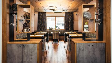 Ein modernes Restaurant mit Holzelementen und stilvollen Regalen. Der Raum ist gut beleuchtet und bietet einen Blick auf den Außenbereich.