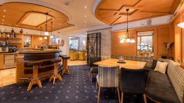 Ein gemütlicher Innenraum mit einer Bar und hellen Holzelementen. Bequeme Sitzgelegenheiten und angenehmes Licht schaffen eine einladende Atmosphäre.