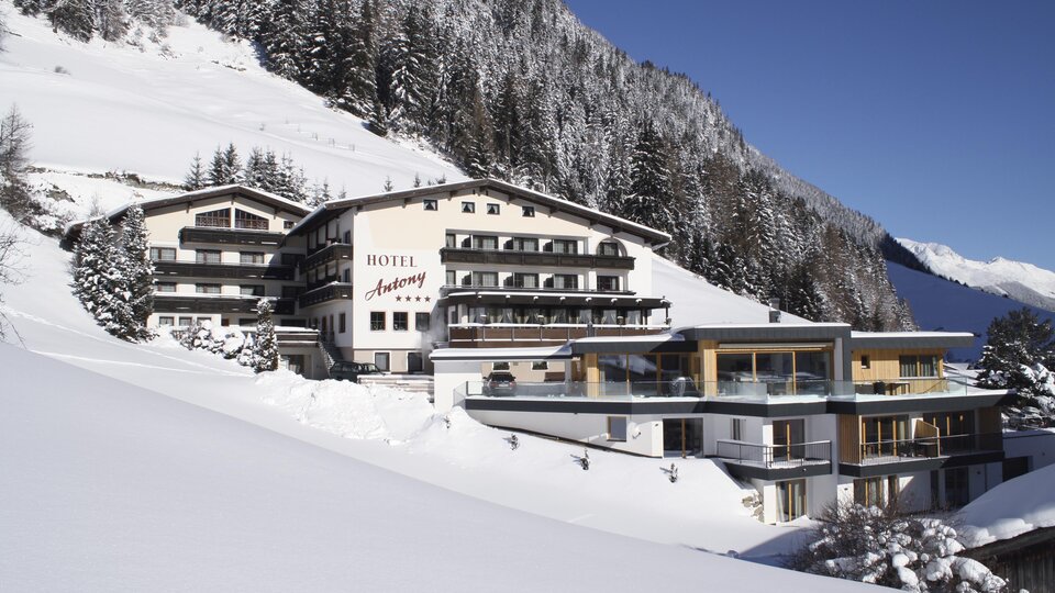 A luxurious hotel in the mountains, surrounded by snow-covered landscapes. The architecture blends traditional design with modern elements.