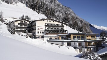 A luxurious hotel in the mountains, surrounded by snow-covered landscapes. The architecture blends traditional design with modern elements.