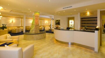 An elegant reception area with a round counter and comfortable sofas. Soft lighting and a decorative water feature create an inviting atmosphere.