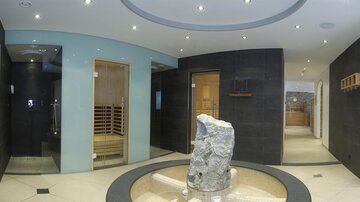 An elegant wellness area with modern facilities and soft lighting. In the center is a natural stone pedestal that gives the room a relaxing atmosphere.