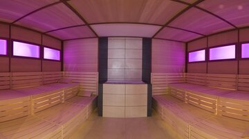 A modern sauna with a wooden bench and soft, pink lighting. The space is cozy and inviting for relaxation.