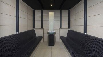 A modern waiting area with two long benches and a small table in the middle. The walls are bright and designed in a minimalist style.