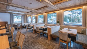 A cozy restaurant with wooden decor and large windows. The inviting tables offer a view of the surrounding landscape.