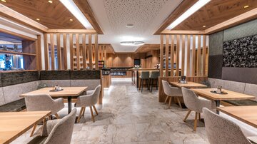 A modern restaurant with wood and stone elements.  
Bright tables and cozy chairs create an inviting atmosphere.