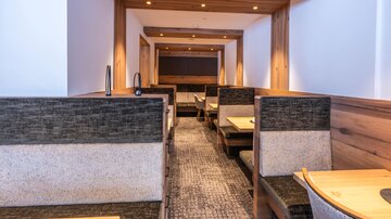 A modern restaurant with cozy seating areas made of wood and neutral colors. The warm lighting creates an inviting atmosphere.