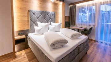 A modern bedroom with a large bed and cozy pillows. The warm wood tones create an inviting atmosphere.