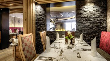 An elegant restaurant with stylish wooden and stone interior. The table is beautifully set and there is a cozy atmosphere.