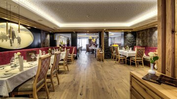 A cozy restaurant with wooden flooring and elegant tables. The walls are tastefully decorated, and the lighting creates an inviting atmosphere.