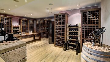 An elegant wine cellar with wooden shelves full of wine bottles. The atmosphere is warm and inviting, ideal for wine lovers.