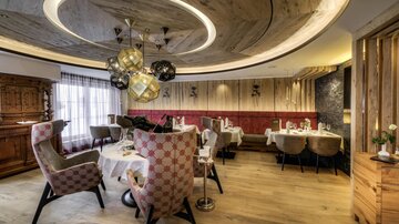 An elegant restaurant with modern chairs and stylish decor. The wooden ceiling and soft lighting create a cozy atmosphere.