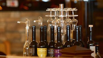 A selection of wine bottles is on a counter, surrounded by glasses. The atmosphere feels inviting and elegant.