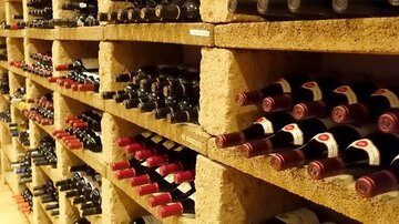 A well-organized wine cellar with several shelves filled with wine bottles. The bottles have various labels and colors.