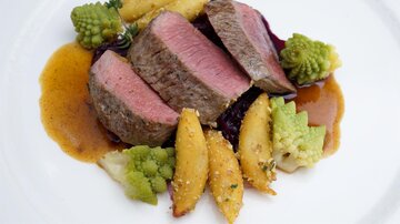 A dish with perfectly cooked beef fillet, served with golden potato wedges and green romanesco. It is topped with an aromatic sauce.
