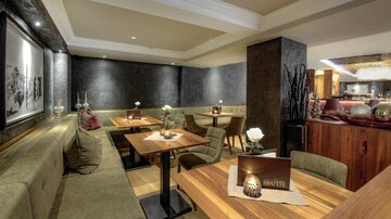A modern restaurant atmosphere with comfortable benches and wooden tables. The lighting is soft and creates an inviting mood.