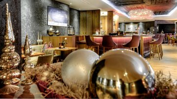 A modern bar with elegant decor and a cozy atmosphere.  
Golden and silver decorative elements give the space a festive touch.