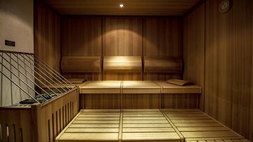 A cozy sauna room made of wood with benches for relaxation. Warm light creates a soothing atmosphere.