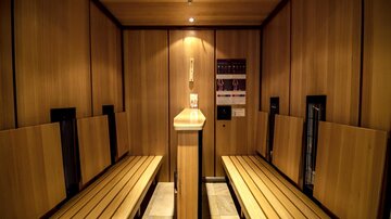 A modern sauna with wooden panelling and benches for relaxing. Soft lighting creates a calm atmosphere.