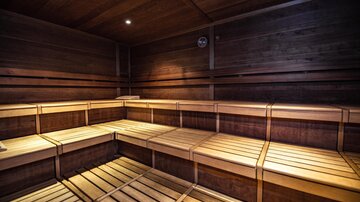 A wooden sauna with light benches and soft lighting. The room radiates relaxation and warmth.