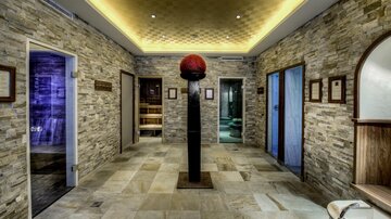 A stylish interior with stone walls and several doors. In the center stands a sculpture with a red dome.