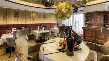 A stylish restaurant with comfortable chairs and elegant lighting. The decor is modern and cozy, with wooden walls and decorative elements.