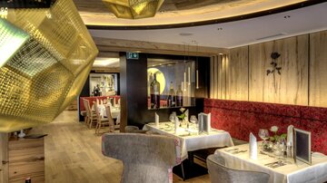 An elegant restaurant with modern furniture and warm wood tones. The space is stylishly decorated and offers a cozy atmosphere.